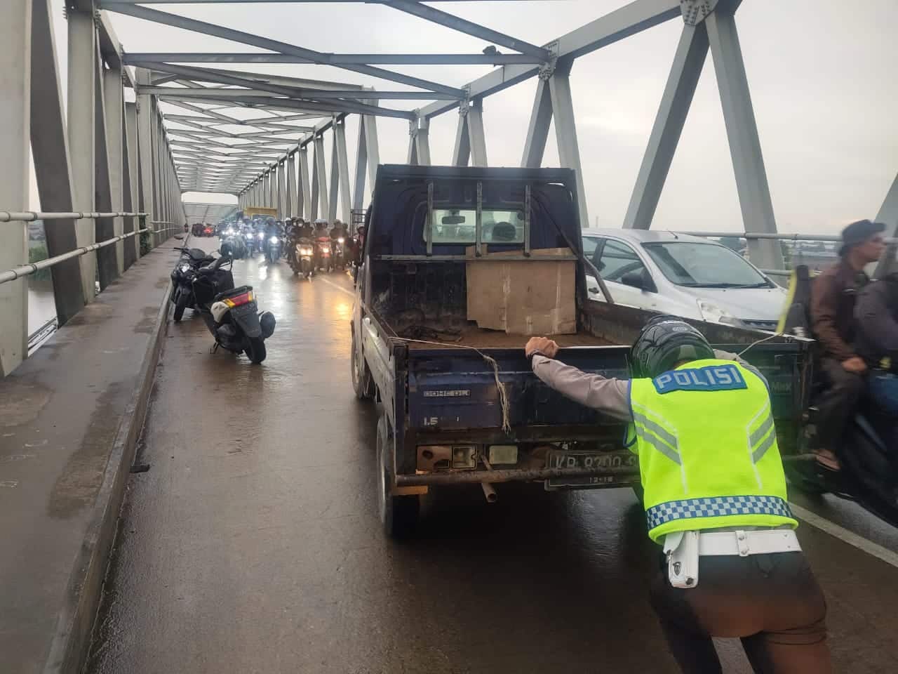 Aksi dua personel Satlantas Polres Kubu Raya mendorong mobil yang sedang mogok di atas jembatan tol Desa Kapur, Sabtu (16/07/2022) sore kemarin. (Foto: Istimewa)