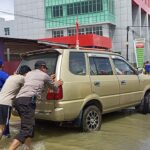 Personel jajaran Polres Kepauas Hulu membantu mendorong mobil warga yang mogok akibat banjir. (Foto: Istimewa)