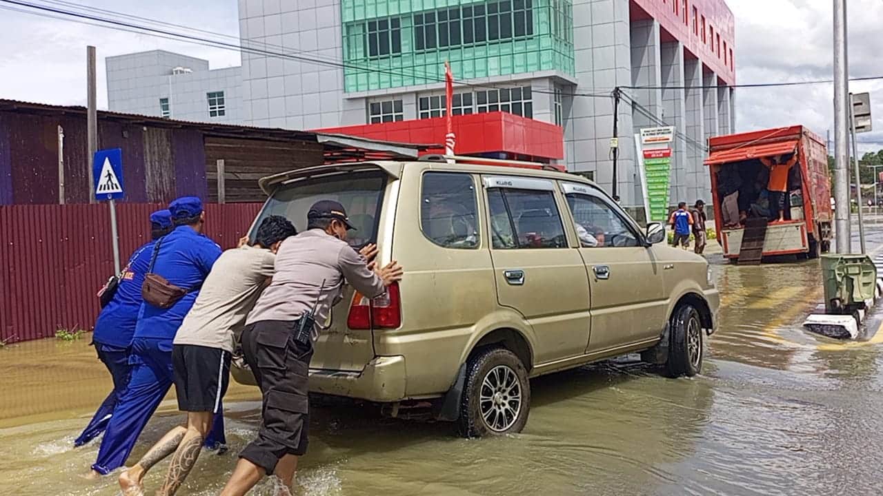 Personel jajaran Polres Kepauas Hulu membantu mendorong mobil warga yang mogok akibat banjir. (Foto: Istimewa)