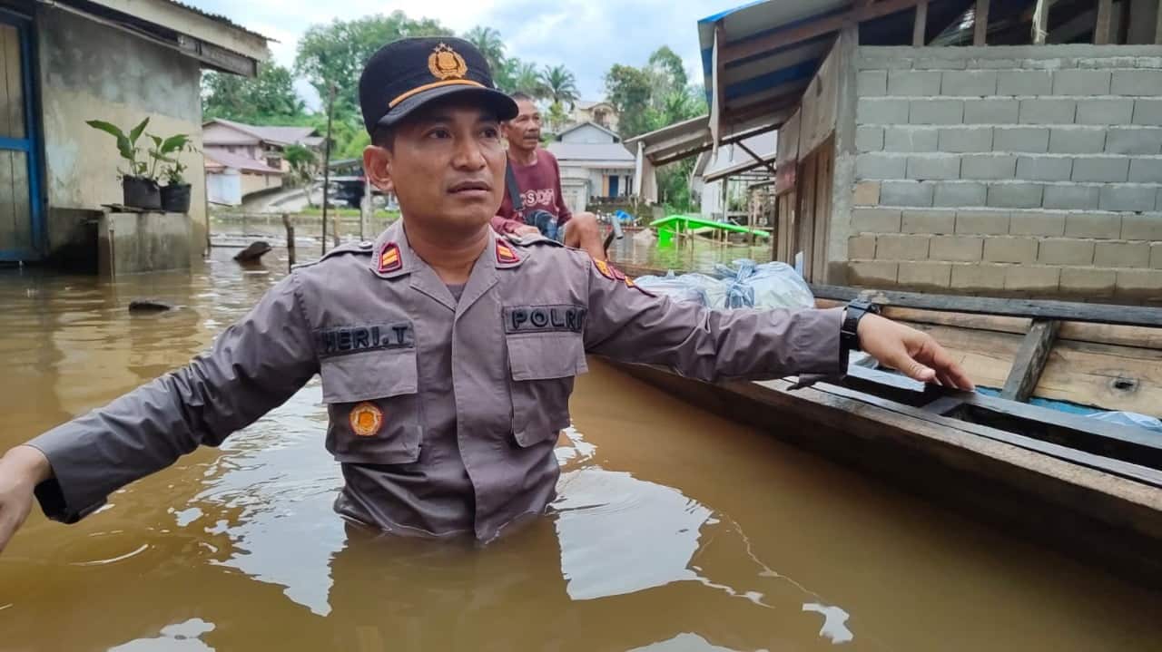 Kapolsek Kapuas jajaran Polres Sanggau, IPTU Heri Triyana menyusuri wilayah banjir di lingkungan Liku, Kelurahan Beringin, untuk memberikan bantun kepada warga terdampak. (Foto: Jauhari)