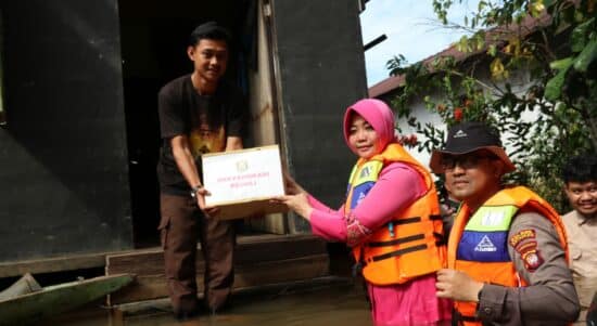 Ketua Bhayangkari Cabang Ketapang, Ayu Yani Permana menyerahkan bantuan sembako kepada warga terdampak banjir di Desa Nanga Tayap, Selasa (18/10/2022). (Foto: Adi LC)