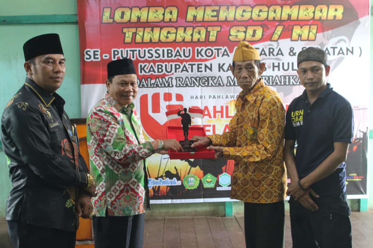 Sekda Kapuas Hulu, Mohd Zaini memberikan plakat dalam acara penutupan perlombaan menggambar tingkat SD/MI yang diadakan oleh lintas organisasi pemuda Kapuas Hulu, Minggu (20/11/2022). (Foto: Ishaq)