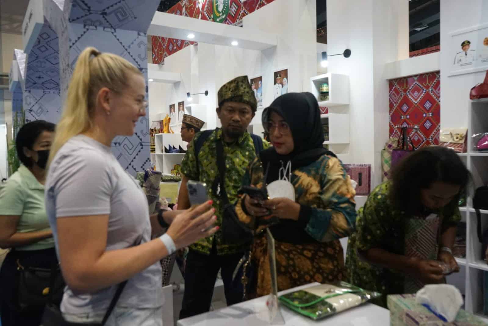 Ketua Dekranasda Kabupaten Kayong Utara, Yayuk Winarti Citra Duani memperkenalkan produk kerajinan Kayong Utara kepada turis asing, pada ajang INACRAFT 2023, di Jakarta Convention Center (JCC), Kamis (02/03/2023). (Foto: Prokopim)