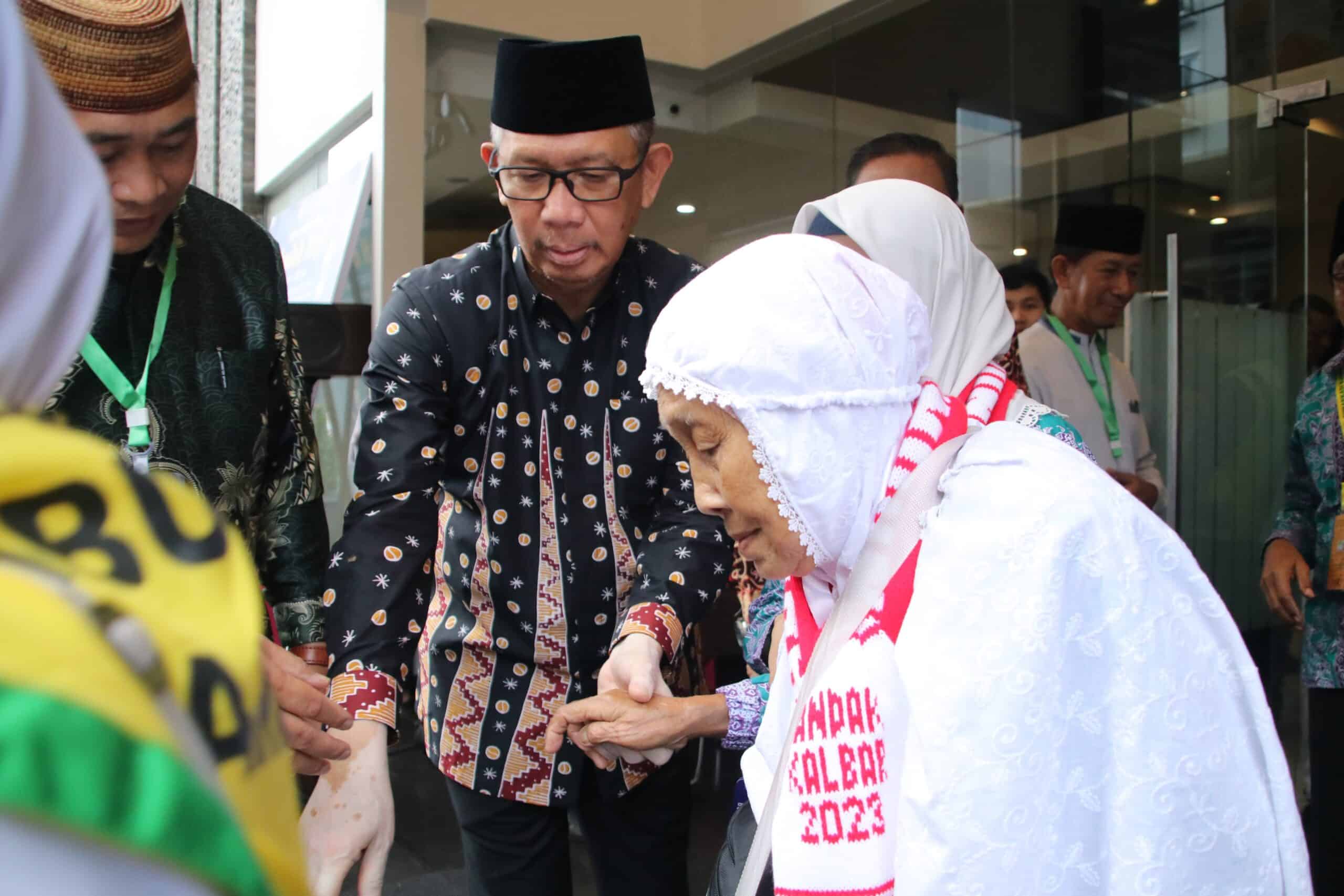Gubernur Kalimantan Barat, Sutarmidji membantu salah satu peserta calon haji menuju bus pemberangkatan di depan Hotel Orchardz Perdana Pontianak, Jumat (16/06/2023). (Foto: Biro Adpim For KalbarOnline.com).