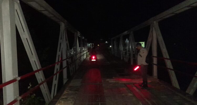 Personel Polsek Pengkadan melakukan pengaturan lalu lintas di jembatan rusak Dusun Sulang. (Foto: Ishaq)