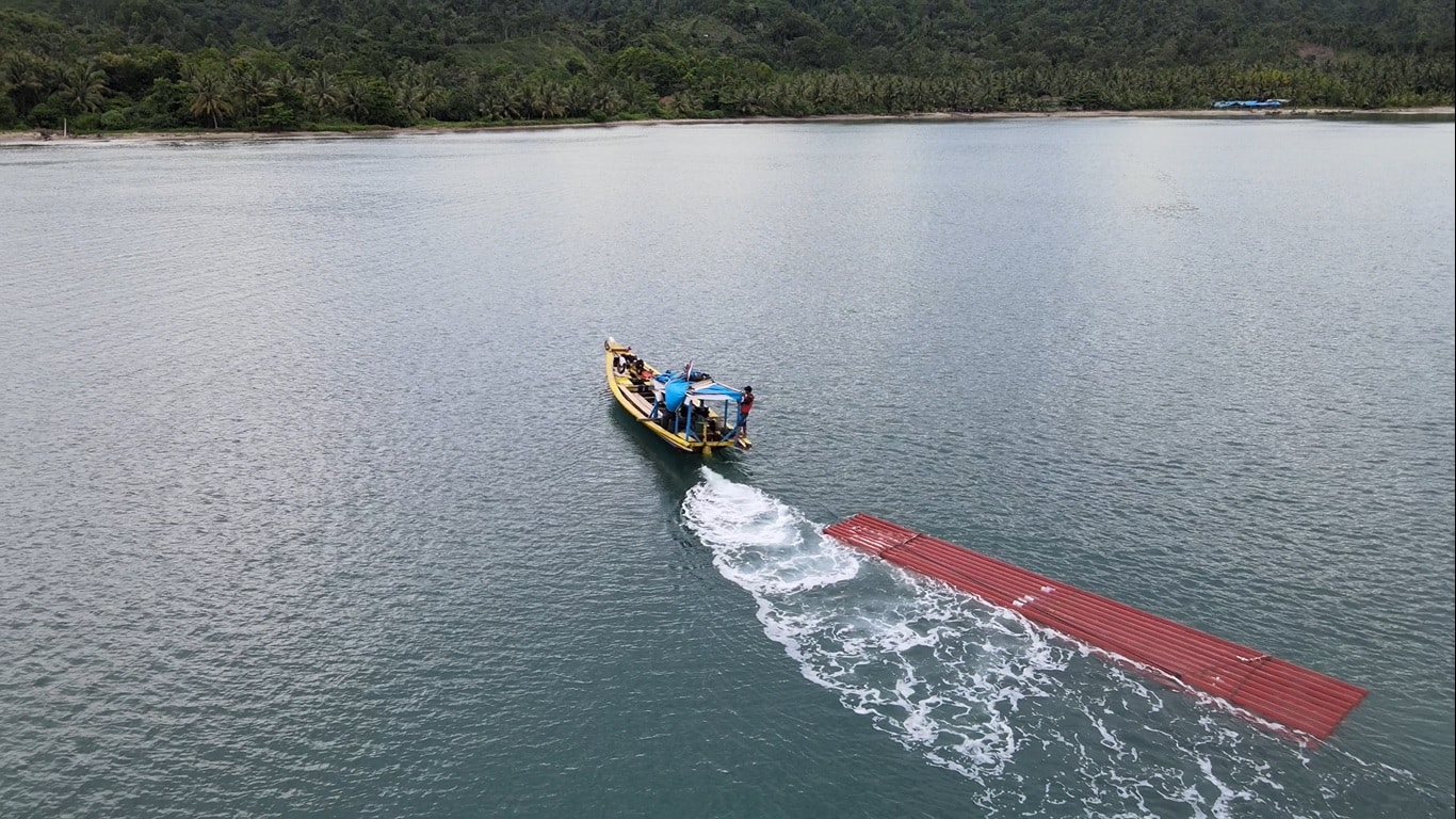Petugas PLN mengirimkan tiang listrik menggunakan kapal untuk melistriki di salah satu desa terpencil di Kabupaten Tanggamus, Lampung. (Foto: PLN)