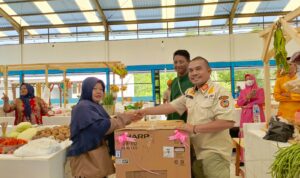 Kepala Satpol PP Kabupaten Kayong Utara, Andri Candra memberikan hadiah kejutan kepada masyarakat yang berbelanja di Pasar Rakyat Sukadana, Kamis (16/11/2023). (Foto: Prokopim/Santo)
