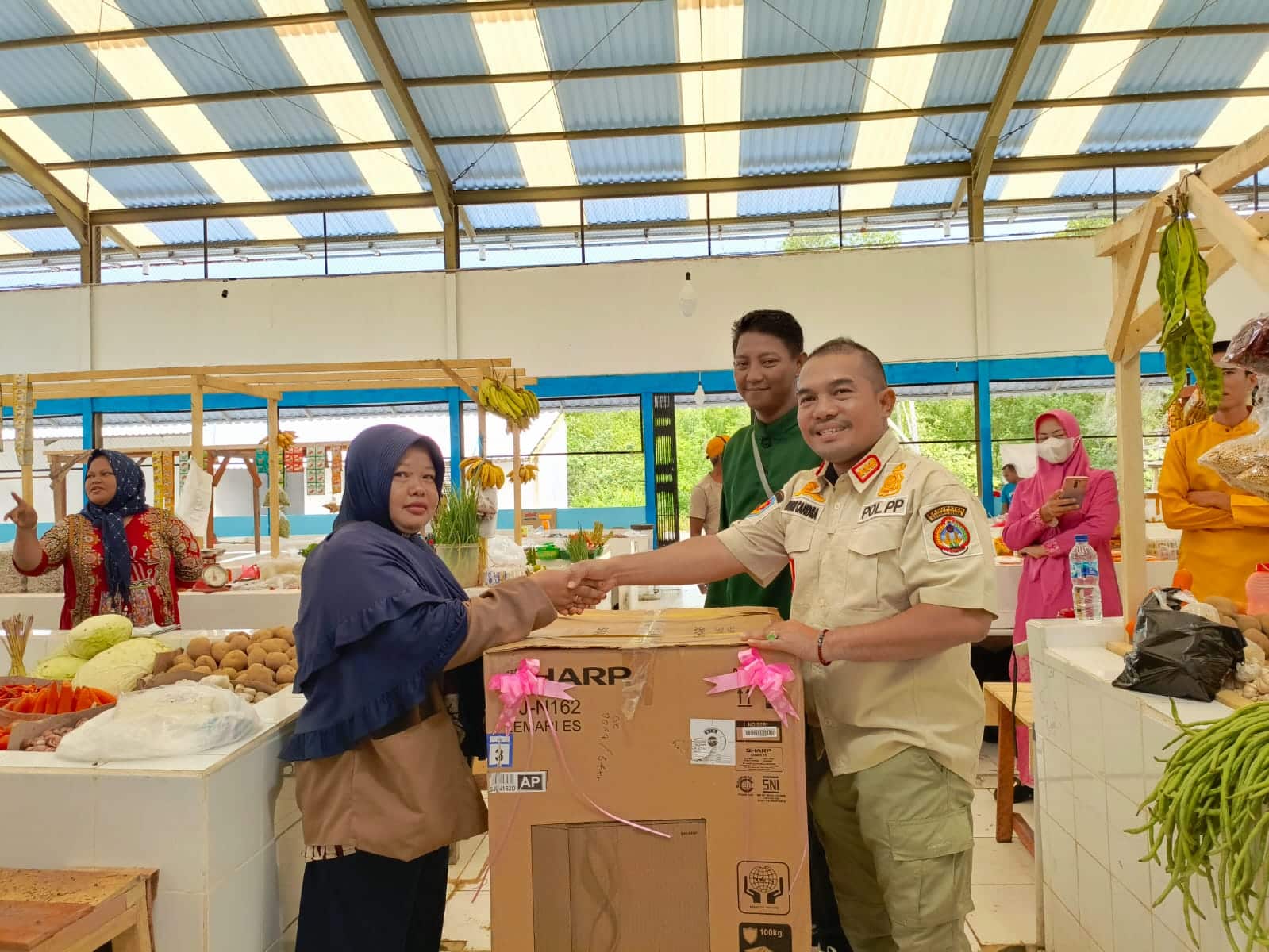 Kepala Satpol PP Kabupaten Kayong Utara, Andri Candra memberikan hadiah kejutan kepada masyarakat yang berbelanja di Pasar Rakyat Sukadana, Kamis (16/11/2023). (Foto: Prokopim/Santo)