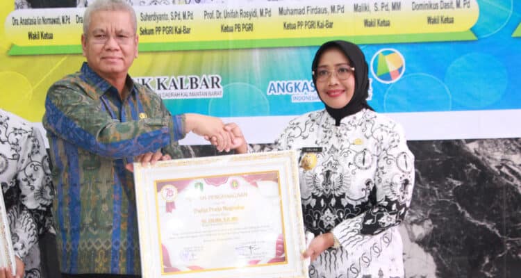 Penjabat Gubernur Kalbar, Harisson menyerahkan penghargaan Widya Praja Provinsi Kalimantan Barat kepada Bupati Mempawah, Erlina atas dedikasinya dalam membangun dunia pendidikan, Sabtu (25/11/2023). (Foto: Jauhari)