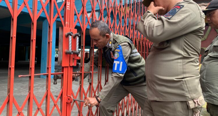 Petugas Satpol PP sedang mencoba merusak paksa gembok gedung Perbasi yang masih dikunci oleh pihak pengelola. (Foto: Indri)