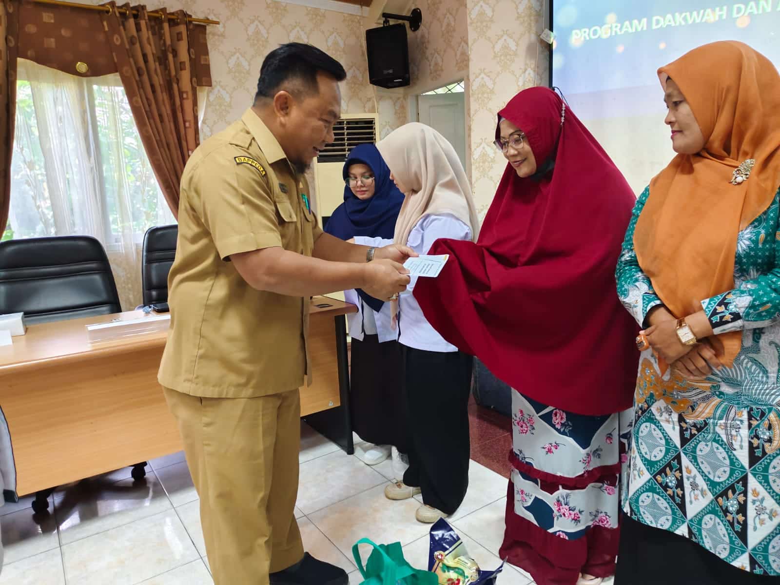 Kepala Bappeda Kota Pontianak, Sidig Handanu menyerahkan tali asih kepada warga kurang mampu. (Foto: Prokopim Pontianak)